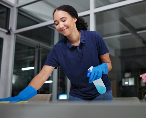 Worker wiping down desk with disinfecting spray